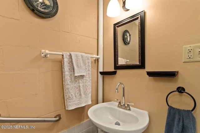 bathroom with concrete block wall and a sink