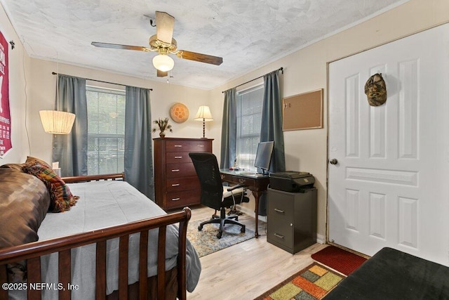 bedroom featuring ceiling fan, light wood-type flooring, and a textured ceiling