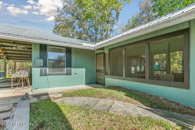 property entrance featuring stucco siding and metal roof