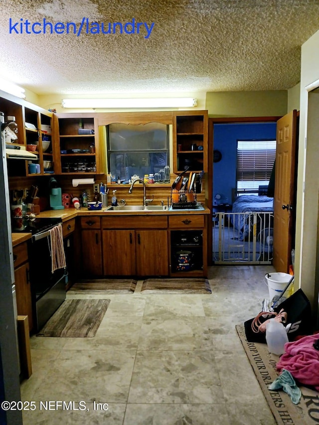 kitchen with a textured ceiling, open shelves, black range with electric stovetop, and a sink