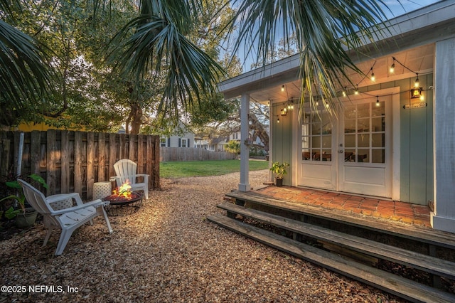 view of yard featuring french doors, an outdoor fire pit, and fence