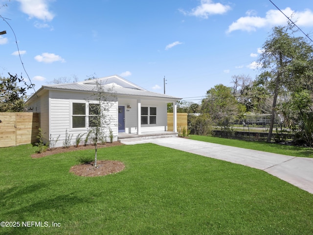 view of front of house featuring metal roof, covered porch, a front yard, and fence