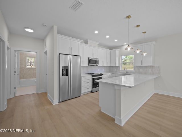 kitchen featuring stainless steel appliances, light wood-style floors, a peninsula, and white cabinetry