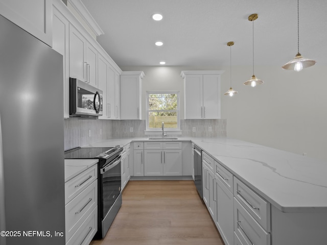 kitchen featuring a sink, white cabinetry, stainless steel appliances, a peninsula, and decorative backsplash