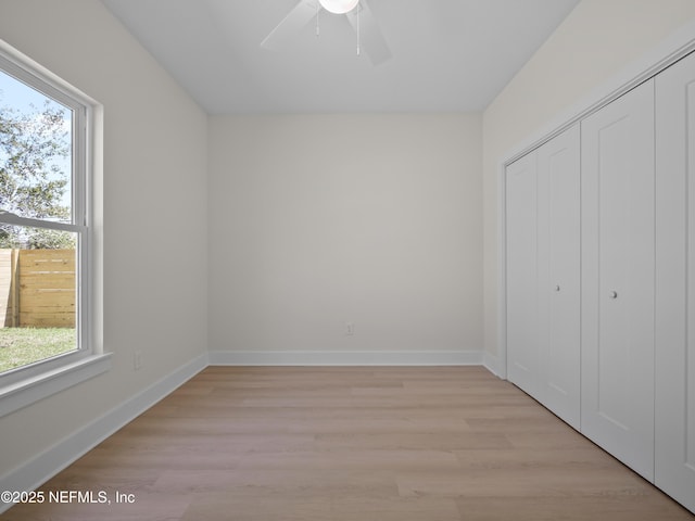 unfurnished bedroom with ceiling fan, a closet, baseboards, and light wood-style flooring