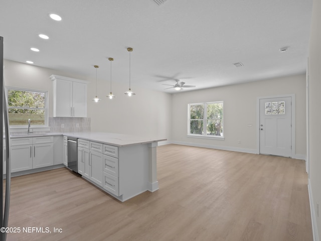 kitchen with a peninsula, ceiling fan, decorative backsplash, stainless steel dishwasher, and open floor plan