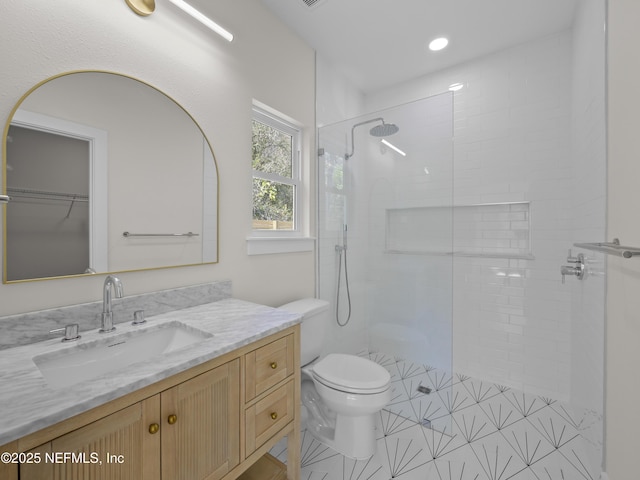 bathroom featuring vanity, toilet, and a tile shower