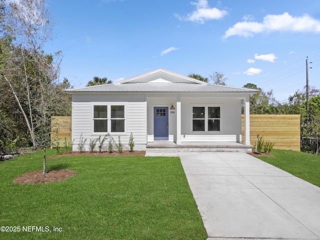 view of front of home with a front lawn, a porch, fence, concrete driveway, and metal roof