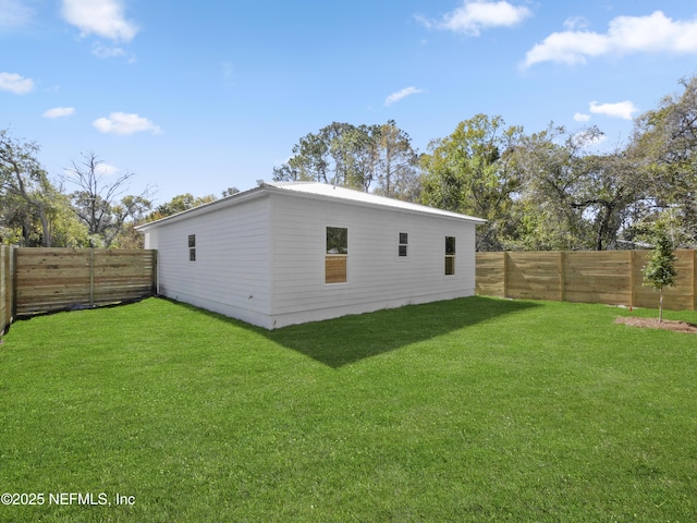 rear view of house with a fenced backyard and a yard