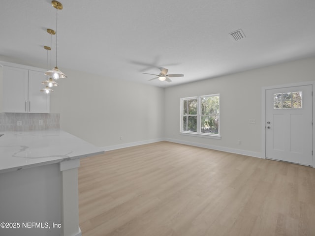 unfurnished living room featuring light wood-type flooring, baseboards, visible vents, and ceiling fan