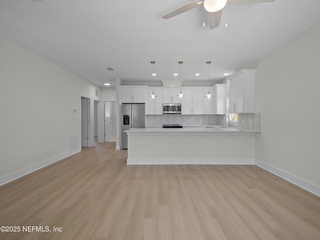 kitchen featuring decorative backsplash, appliances with stainless steel finishes, light countertops, and a peninsula