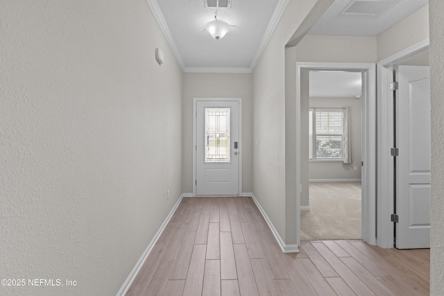 doorway featuring light wood-type flooring, visible vents, baseboards, and crown molding