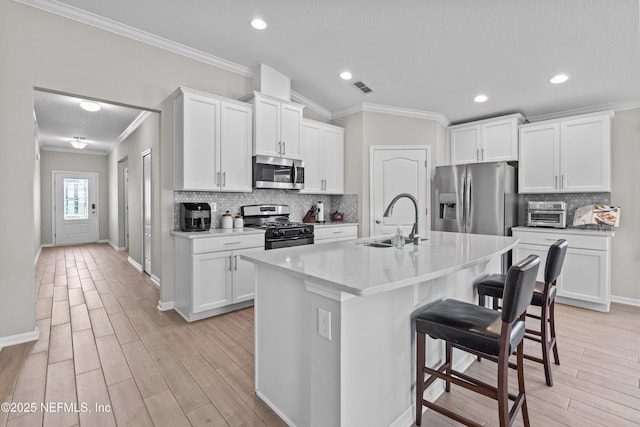 kitchen with a kitchen bar, visible vents, a sink, stainless steel appliances, and light wood-style floors