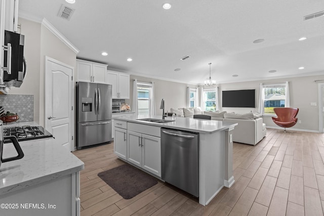 kitchen with visible vents, stainless steel appliances, wood tiled floor, and a sink