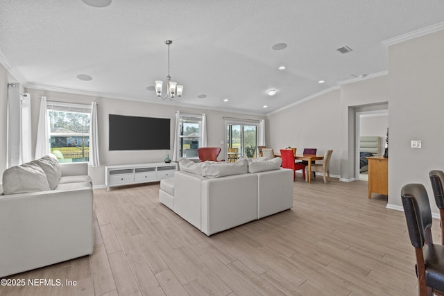 living room featuring a wealth of natural light, visible vents, light wood finished floors, and a chandelier