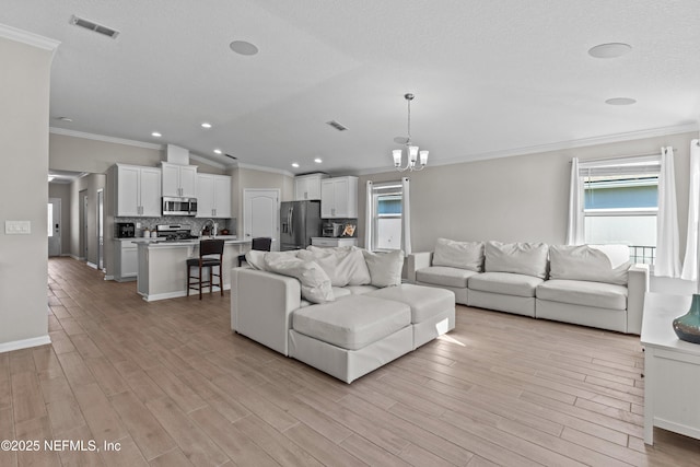 living area featuring light wood-style floors, visible vents, and a chandelier