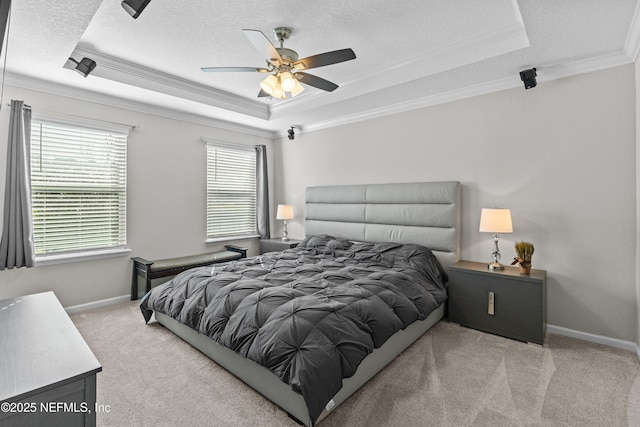 carpeted bedroom featuring a textured ceiling, a raised ceiling, baseboards, and ornamental molding