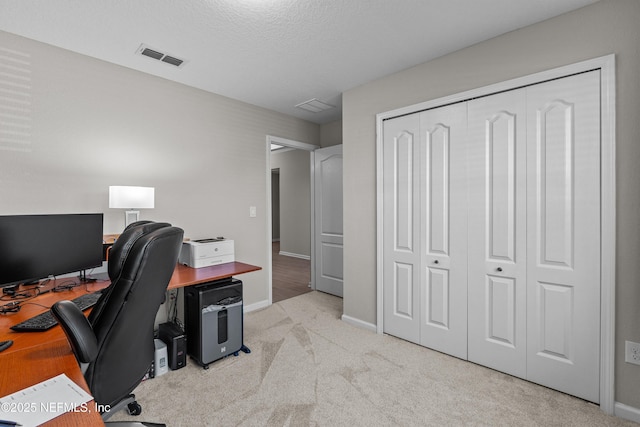 carpeted office space featuring visible vents, baseboards, and a textured ceiling