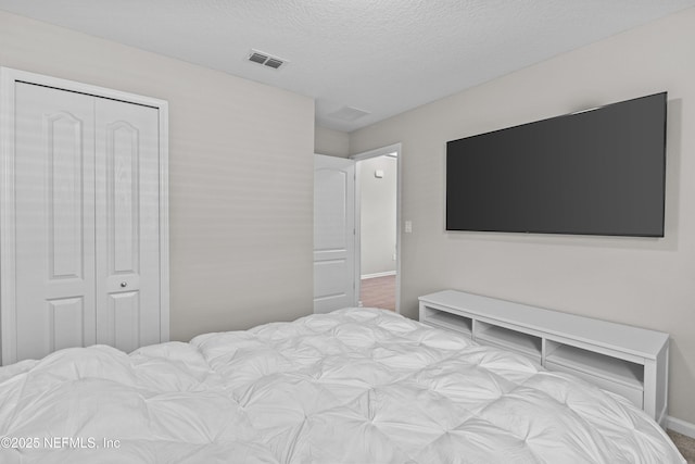 bedroom featuring baseboards, visible vents, a closet, and a textured ceiling