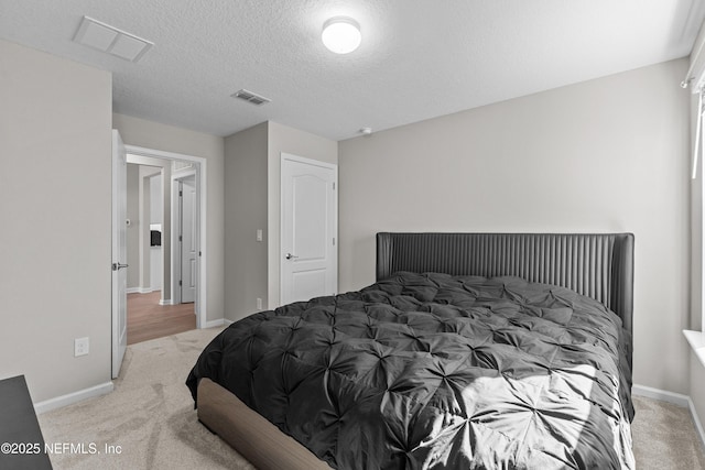 carpeted bedroom with visible vents, a textured ceiling, and baseboards