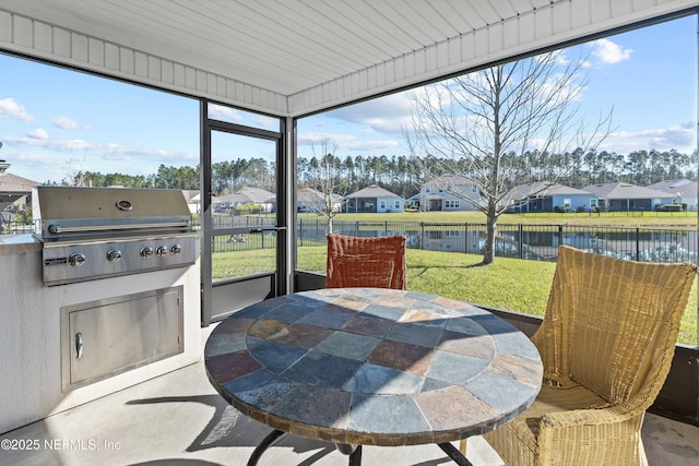 sunroom / solarium featuring a residential view and a water view