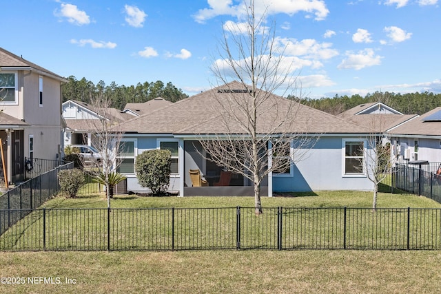 back of property with a fenced front yard, a yard, a shingled roof, and stucco siding