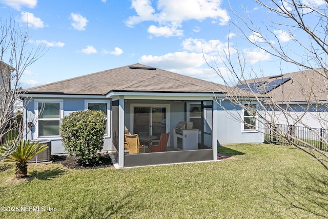 back of property with a lawn, a sunroom, and stucco siding