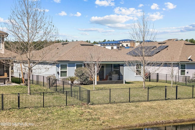 rear view of house featuring a lawn, roof with shingles, a fenced backyard, and stucco siding