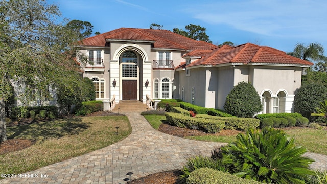 mediterranean / spanish home with stucco siding, a tiled roof, and a balcony