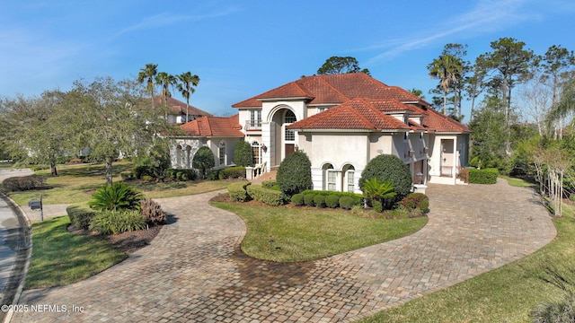 mediterranean / spanish-style home with stucco siding, a front lawn, and a tile roof