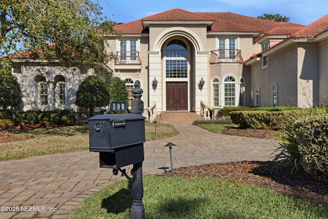 mediterranean / spanish house featuring stucco siding, a tile roof, and a balcony