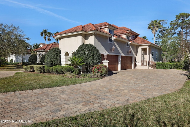 mediterranean / spanish-style house with stucco siding, a tiled roof, decorative driveway, and a garage