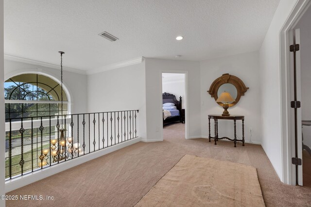 corridor with visible vents, baseboards, carpet floors, an inviting chandelier, and a textured ceiling