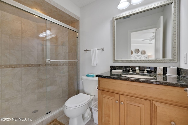 bathroom with toilet, a stall shower, vanity, and a ceiling fan