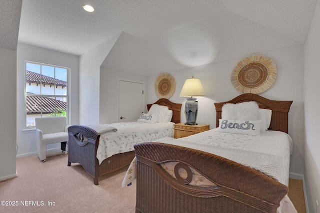 bedroom with baseboards, light carpet, and a textured ceiling