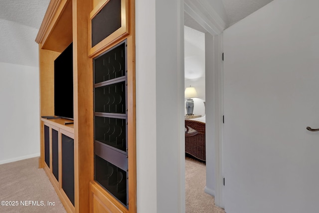 corridor with baseboards and light colored carpet