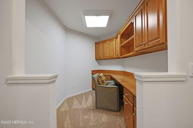 office with baseboards, light colored carpet, and built in desk