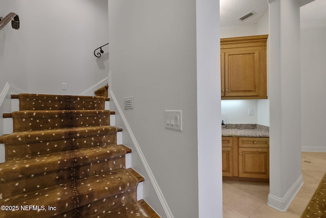 stairs featuring tile patterned floors, baseboards, and visible vents