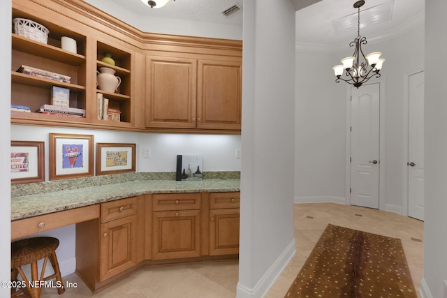 kitchen with light stone counters, visible vents, built in study area, crown molding, and decorative light fixtures