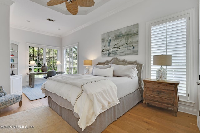 bedroom with ceiling fan, visible vents, wood finished floors, and ornamental molding