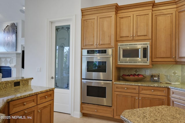 kitchen featuring light tile patterned floors, light stone counters, decorative backsplash, appliances with stainless steel finishes, and brown cabinets