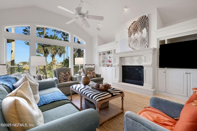 living area featuring built in features, a ceiling fan, a healthy amount of sunlight, and a high end fireplace