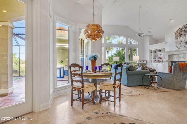 dining area featuring a ceiling fan, vaulted ceiling, light tile patterned floors, and a fireplace