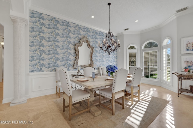 dining space featuring a notable chandelier, ornamental molding, wainscoting, wallpapered walls, and decorative columns