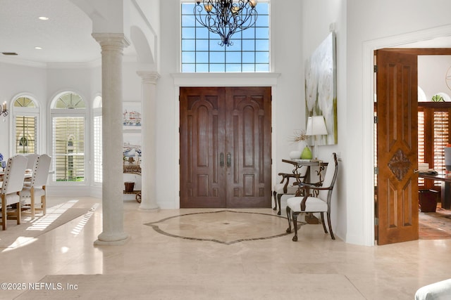 entryway featuring a towering ceiling, arched walkways, ornate columns, and ornamental molding