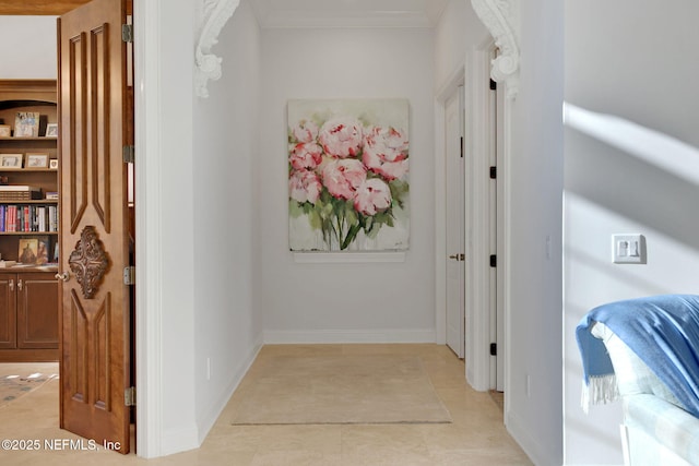 corridor featuring light tile patterned floors, baseboards, and ornamental molding