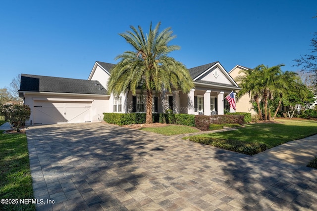 view of front of home with stucco siding, an attached garage, decorative driveway, and a front lawn