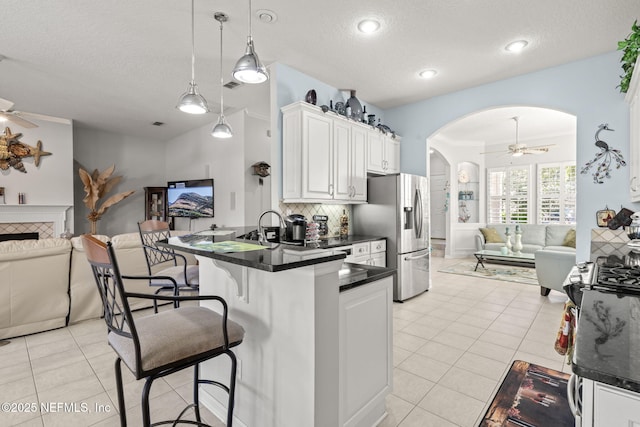 kitchen featuring a breakfast bar, dark countertops, open floor plan, arched walkways, and ceiling fan