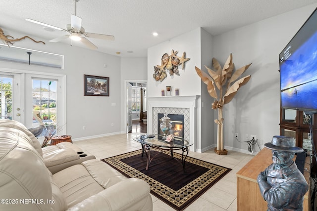 living area with light tile patterned floors, baseboards, a textured ceiling, and a tiled fireplace