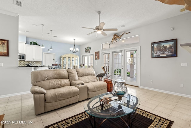 living room with light tile patterned floors, ceiling fan with notable chandelier, visible vents, and a textured ceiling